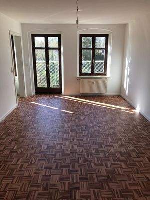 Wohnzimmer mit Zugang zur Küche und zum Balkon