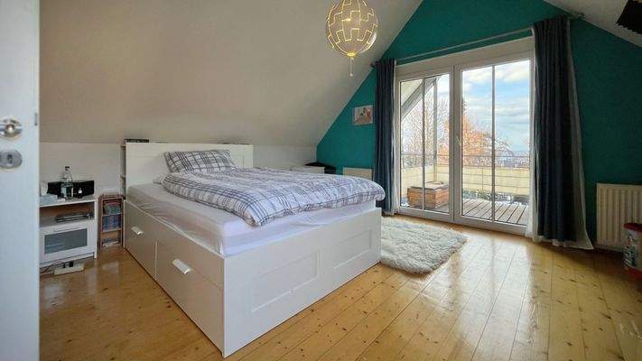 Das zweite Schlafzimmer im Dachgeschoss bietet direkten Zugang zum überdachten Balkon