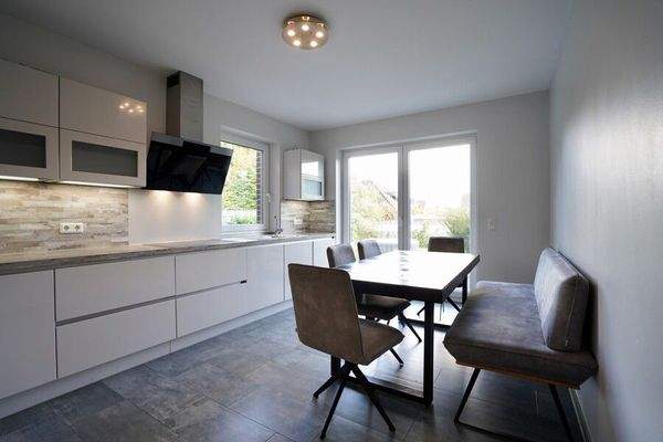 Moderne Küche mit ausreichend Platz für eine Sitzgelegenheit und mit Zugang zur Terrasse