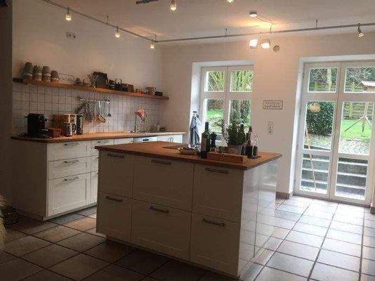 Küche mit Insel und Ausgang zum Garten