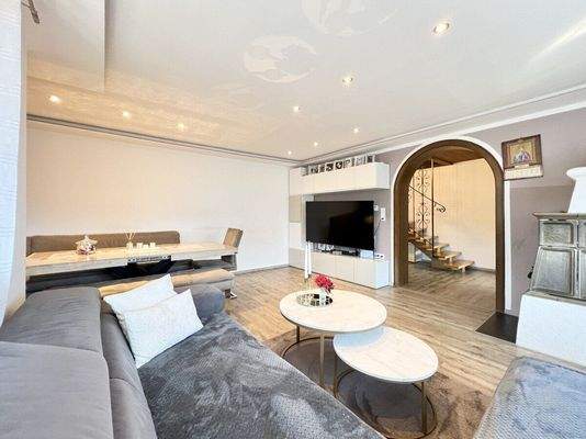 Wohn-Esszimmer mit gemütlichem Kachelofen und Zugang auf den Balkon