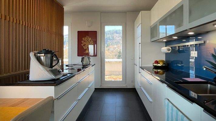 Offen gestaltete Küche mit natürlichem Licht und direkter Terrassenanbindung