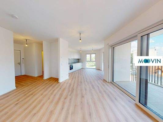 Ansicht II: Wohn- und Esszimmer mit offener Küche und Zugang zum Balkon