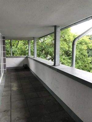 Überdachter Balkon mit grauen Betonfliesenboden
