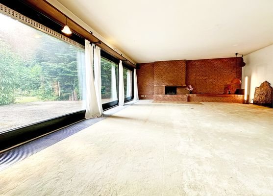 Großes Wohnzimmer mit Kamin und großen Panoramascheiben