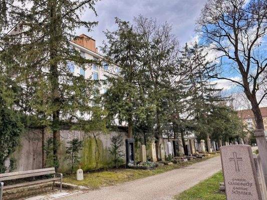 Friedhof mit angrenzender Mauer neben dem Haus