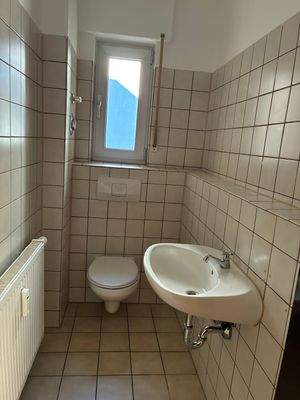 WC mit Fenster, weißen Sanitärobjekten, beigen Wand- und Bodenfliesen