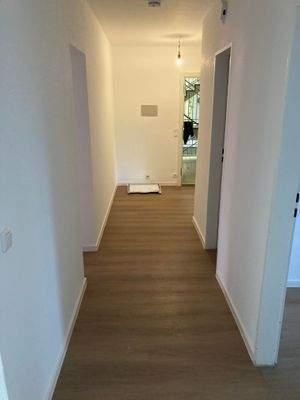 Flur mit weißen Wänden, braunem Vinylboden