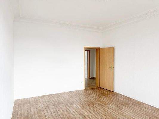 Wohnzimmer mit Stuckdecke und Blick Richtung Flurbereich