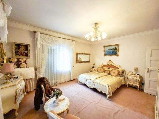 Großes Schlafzimmer mit seitlichem Balkon und angrenzendem Badezimmer