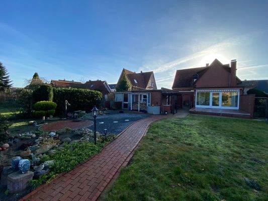 Blick aus dem Garten auf Wintergarten und Rückseite des Hauses sowie der Garagen