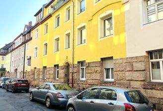 Fassade mit Anliegerparkplätzen vor dem Haus