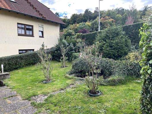 viel grün, gepflegter Garten mit Sträuchern, Rasenfläche und kleinem Teich