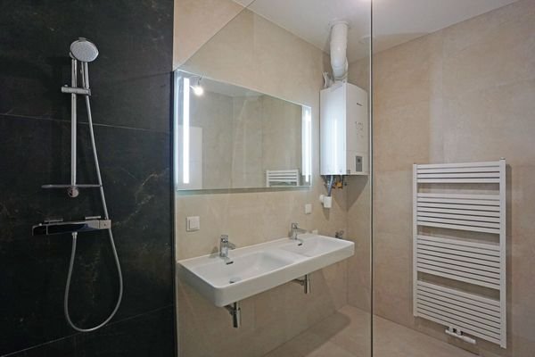 Badezimmer mit Doppelwaschbecken, Dusche, Handtuchheizkörper und Gas-Brennwertgerät