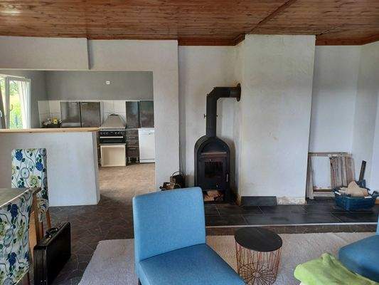 Wohnzimmer mit Ofen und Blick in die Küche