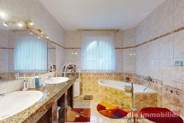 Eines von drei Bädern – mit großer Eckwanne, Doppelwaschplatz und warmen Naturtönen.