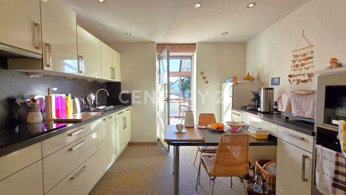 Helle Küche mit Steinteppich und Zugang zur Terrasse