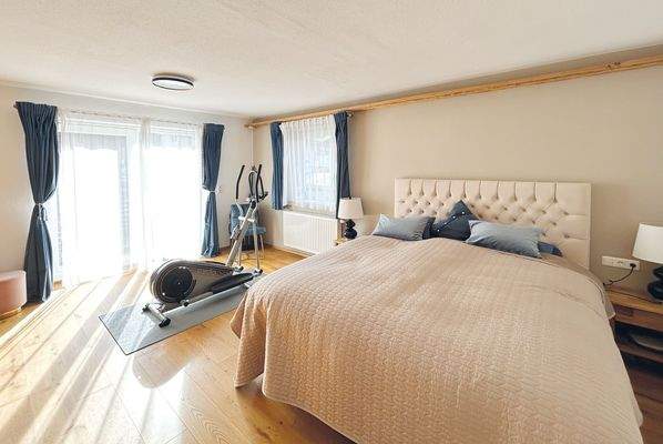 geräumiges Schlafzimmer mit indirekt beleuchteten Einbauschränken und Zugang zum Balkon