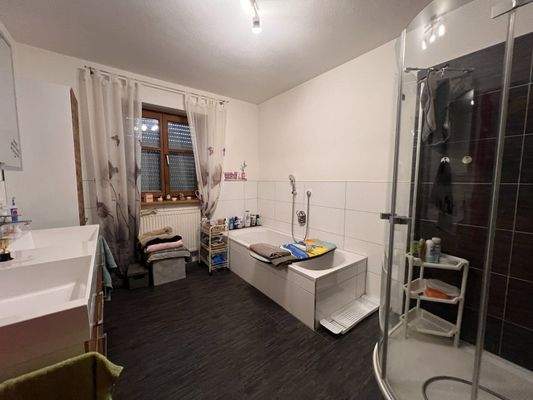 Geräumiges Badezimmer mit Badewanne, Dusche und praktischer Stauraumlösung