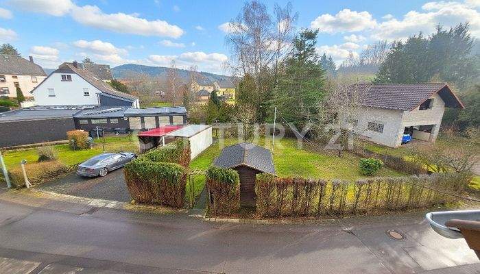 Blick über den Garten und die Garage mit Stellplätzen davor