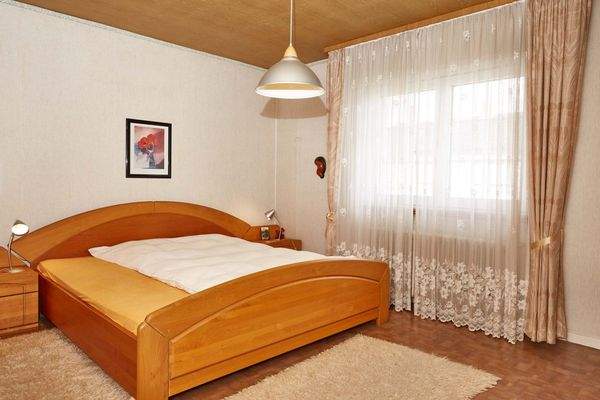 Helles Schlafzimmer mit großflächigen Fenstern und hochwertiger Ausstattung