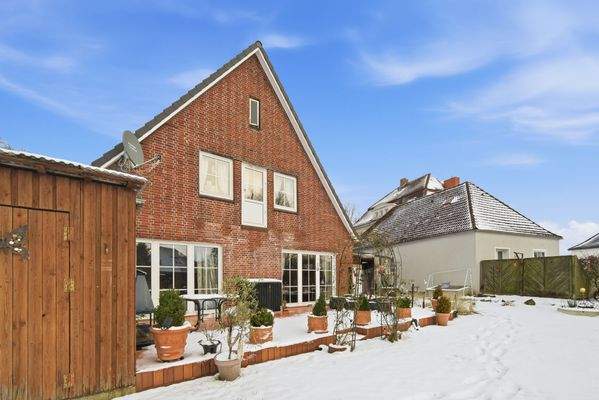 Hausrückseite mit Terrasse und großem Garten