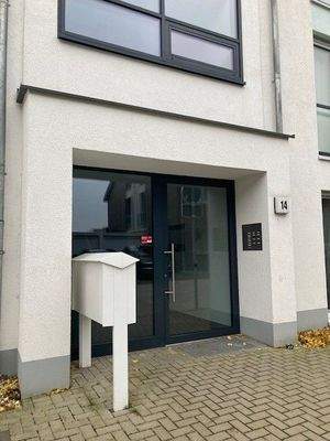 Blick auf den Hauseingang des weißen Hauses mit grauer Glaseingangstür