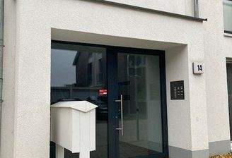 Blick auf den Hauseingang des weißen Hauses mit grauer Glaseingangstür