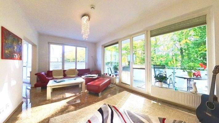 Großzügiges Wohnzimmer mit raumhohen Fenstern und Zugang zum Südbalkon