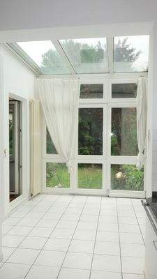 Küchenbereich mit Wintergarten und Ausgang über eine massive Treppe in den Garten.