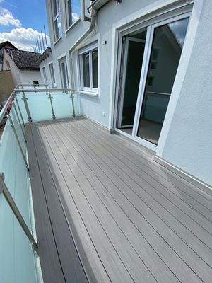 breiter sonniger Balkon mit hellgrauen WPC-Belag.j