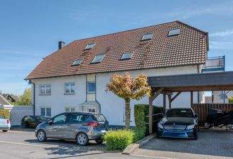 Hausansicht mit Parkplätzen und Carport