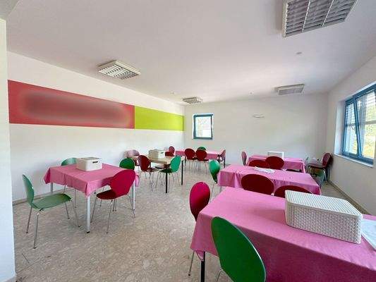 weiterer Raum mit Tischen und Fenstern