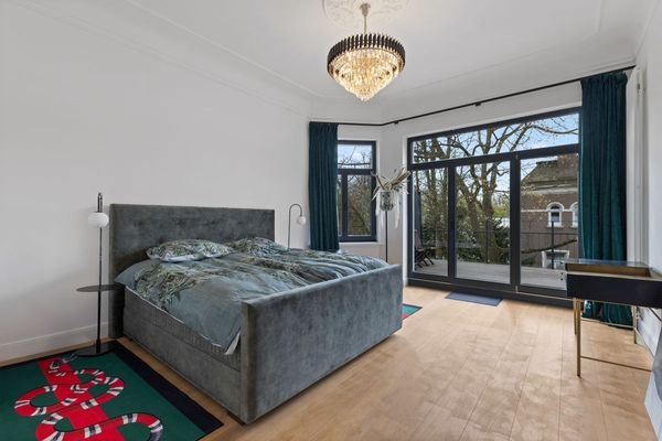 Hauptschlafzimmer mit großer Fensterfront und Balkon
