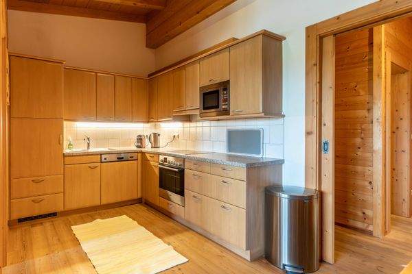 Geräumige Küche mit Holzfronten, Elektrogeräten, Mikrowelle und viel Arbeitsfläche.
