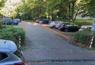 Parkplatz Ansicht mit Beschriftung der Stellplatznummern umgeben von Bäumen und Sträuchern. 