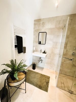Badezimmer mit Dusche, Waschbecken und Waschmaschinenanschluss