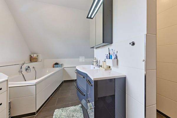 Im Badezimmer mit Dusche, Wanne und Fenster