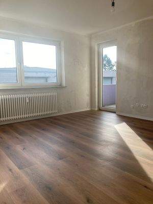 Wohnzimmer mit neuem Bodenbelag in Holzoptik, Wände sind tapezierfertig vorbereitet