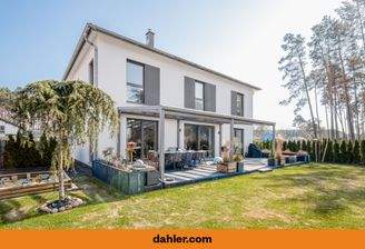 Sonnige Gartenansicht mit weitläufiger Terrasse und moderne Architektur