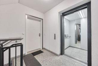 Einladender Eingangsbereich mit Aufzug und gepflegtem Treppenhaus