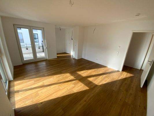 Wohn- und Essbereich mit weißen Wänden, Vinylboden in Holzoptik und Fenstern