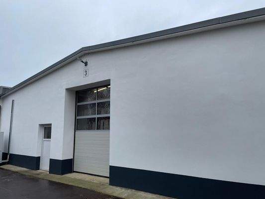 Gepflegte Hallenfassade mit Sektionaltor und separatem Eingang