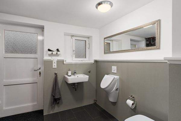 Gäste-WC mit Waschbecken, WC und Urinal sowie direktem Zugang zur Terrasse bzw. zum Garten.