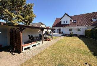 Carport mit Sitzmöglichkeiten und Hof mit Blick zum Haus