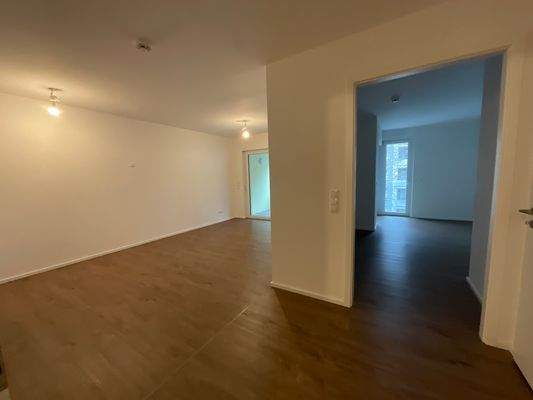 Beispielhafte Wohnung: Blick Richtung Wohnbereich und Schlafzimmer; weiß angelegte Wände und brauner Vinyl-Designboden in Holzoptik