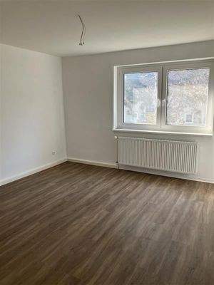 Zimmer mit Fußboden in Holzoptik, Doppelfenster und Heizkörper 