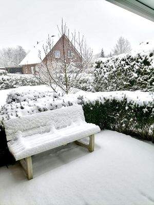 Verschneite Gartenbank auf der Terrasse