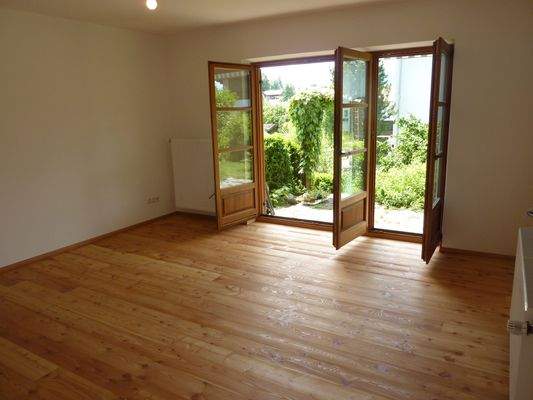 Wohnzimmer - ohne Möbel - Blick zur Terrasse und Garten im Sommer