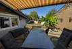 Sonnige Gartenterrasse mit gestreifter Markise